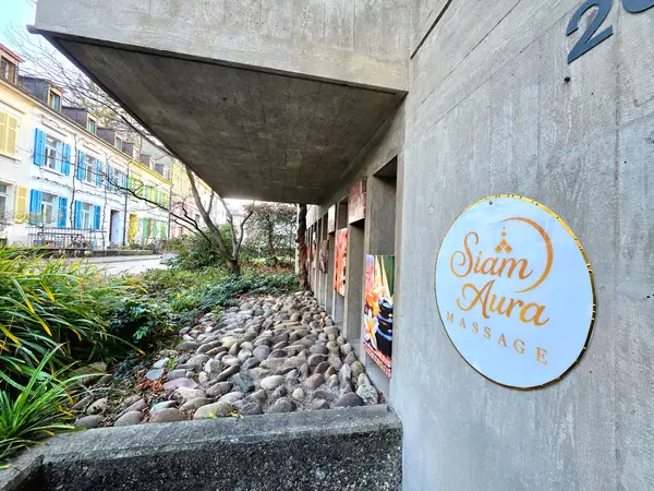 Exterior concrete walkway with Siam Aura Massage sign and landscaped stones