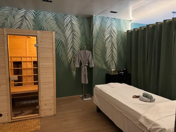 Spa room with massage table, sauna, and tropical leaf wallpaper