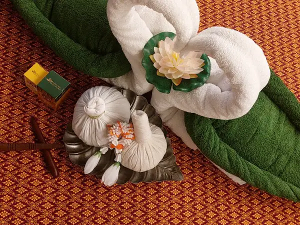 Decorative Thai massage display with rolled towels and lotus flowers on patterned carpet