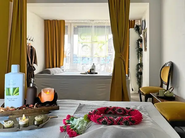 Cozy massage room with beds, mustard curtains, candles, and floral garlands
