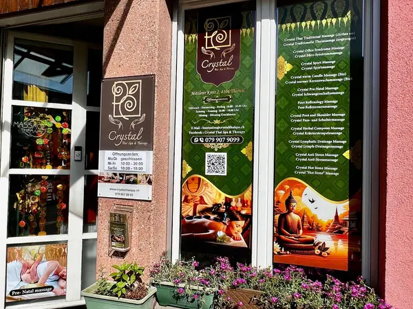 Exterior storefront with green massage-service signs, flower boxes, and Thai decor