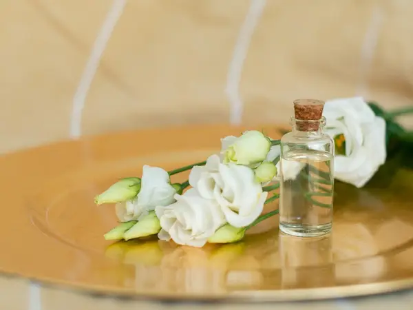 White flowers and a small glass bottle on a golden tray