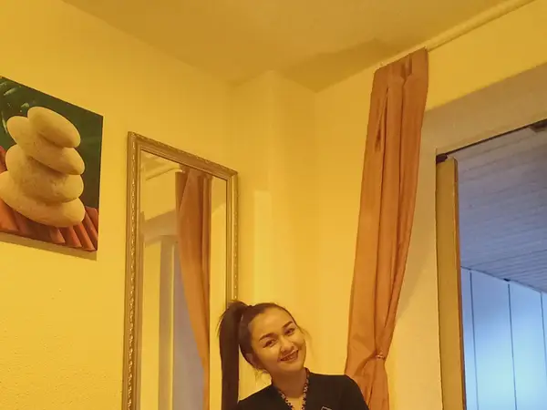 Warm massage room with mirror, spa poster, curtains, and smiling woman