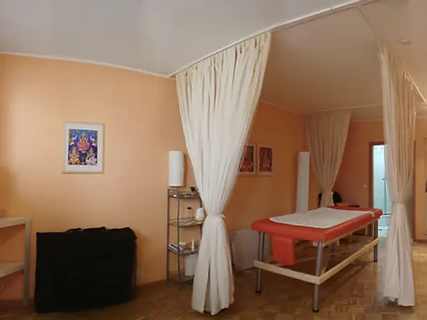 Peach massage room with curtained tables, framed art, and warm lighting
