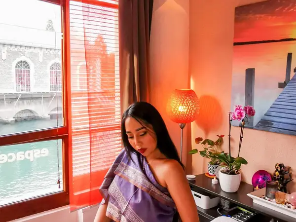 Warm massage room with window, orange lamp, plants, and wall art