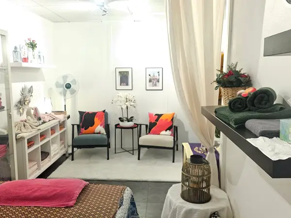 Bright massage room with chairs, folded towels, and colorful cushions