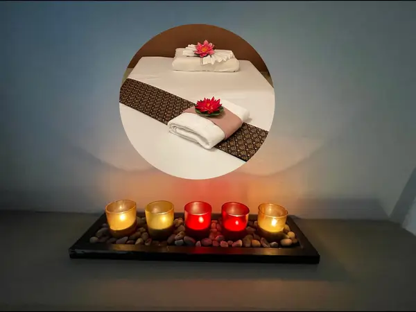 Massage room with lit candles, folded towels, and flower decorations