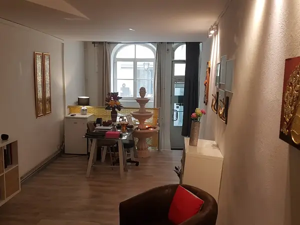 A softly lit massage room with a desk, flowers, and decorative wall art
