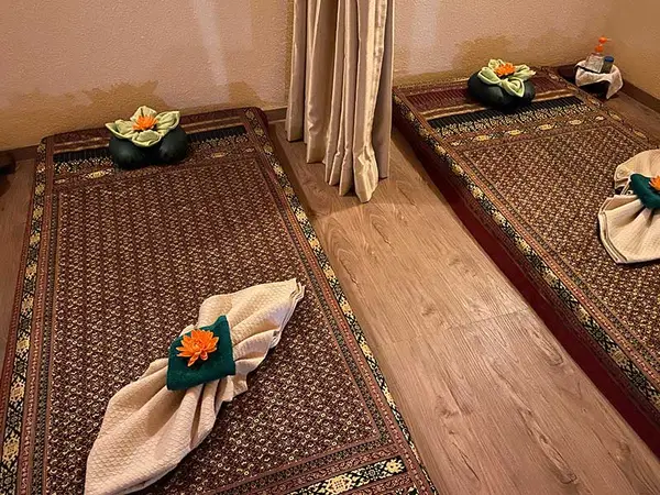 Tranquil massage room with two floor mats, folded towels, and flower decorations