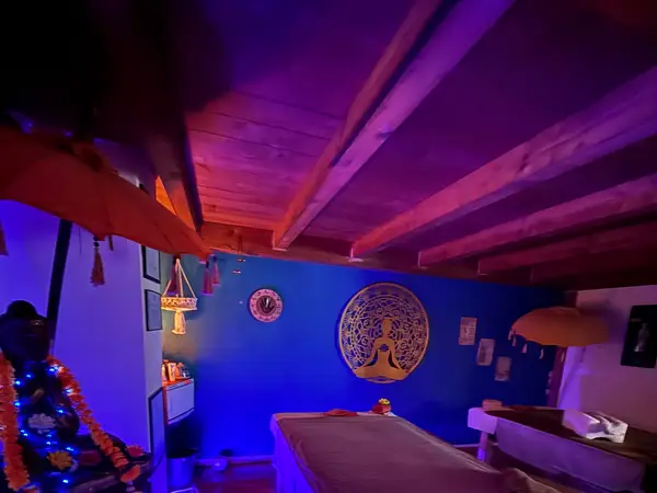 Dim Thai massage room with blue walls, wooden ceiling, and treatment tables