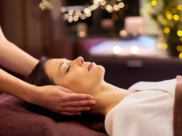 Woman receiving a head massage in a softly lit spa room