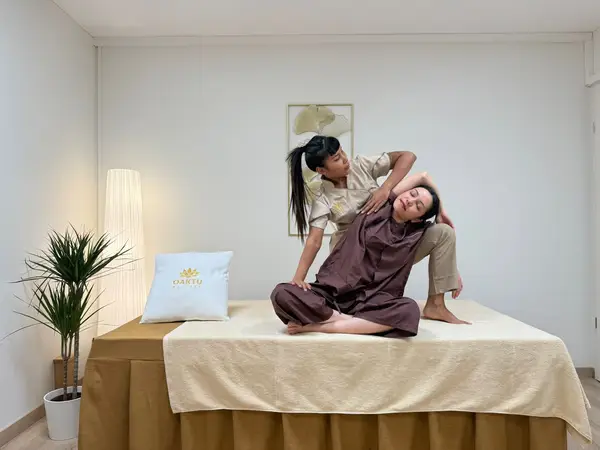 Bright massage room with therapist stretching a seated client on a treatment table