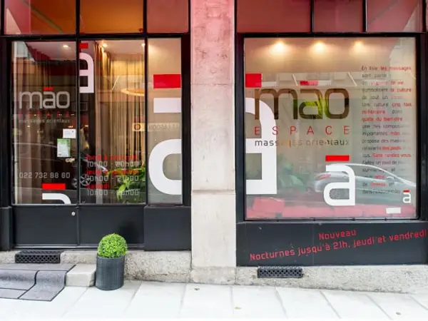 Exterior storefront with large windows, signage, and a potted plant