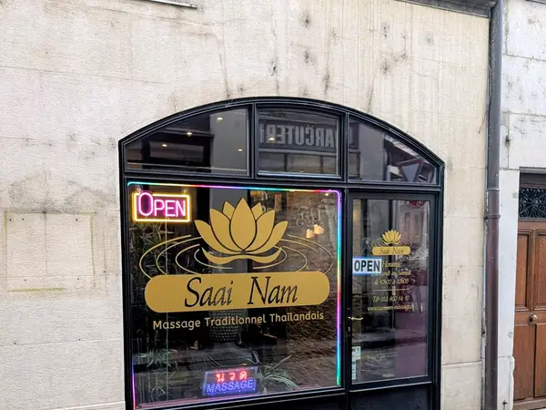Exterior storefront of Saai Nam Massage with neon OPEN sign and lotus logo