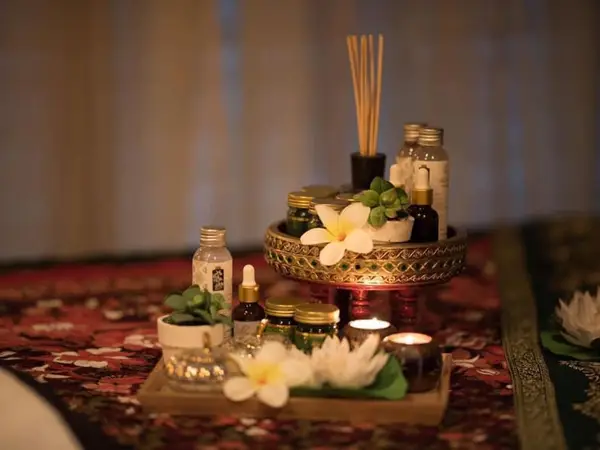 Thai massage room with candles, oils, flowers, and incense on patterned rugs