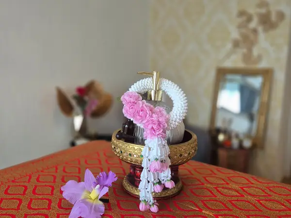 Decorative massage room with floral garland, ornate oil bottle, and patterned tablecloth