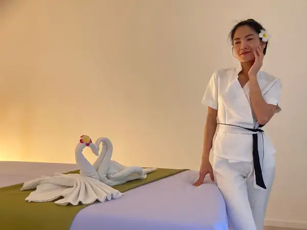 Massage room with towel swans and a smiling therapist in white uniform