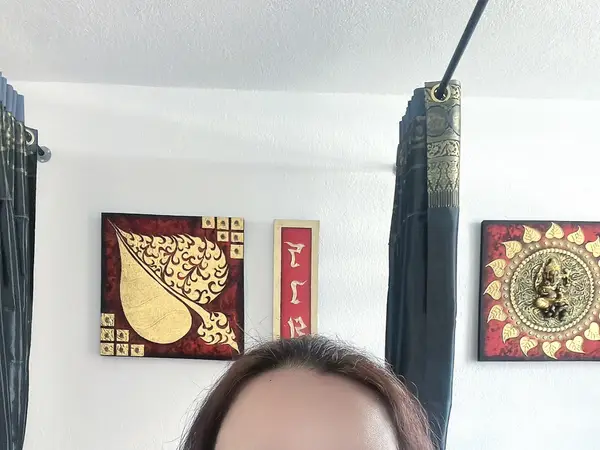 Thai massage room with white walls, black curtains, and Thai-style wall art
