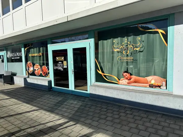 Thai massage storefront with teal door, large window graphics, and sidewalk outside