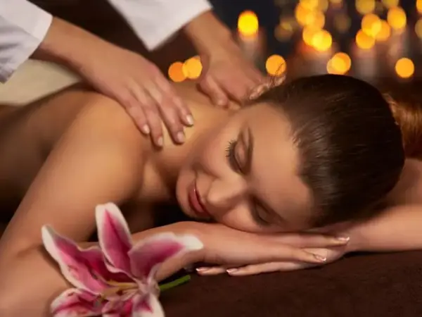 Spa massage scene with candlelit background and a woman resting on the table