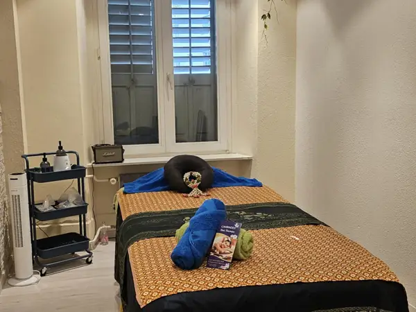 Small massage room with two treatment beds, towels, and a window