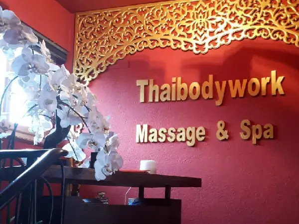 Red spa lobby with gold Thai-style wall decor and white orchids