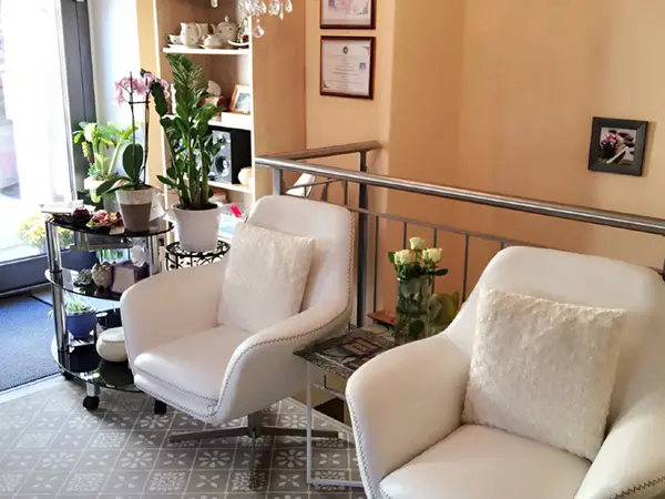 Bright waiting area with white chairs, plants, and warm beige walls
