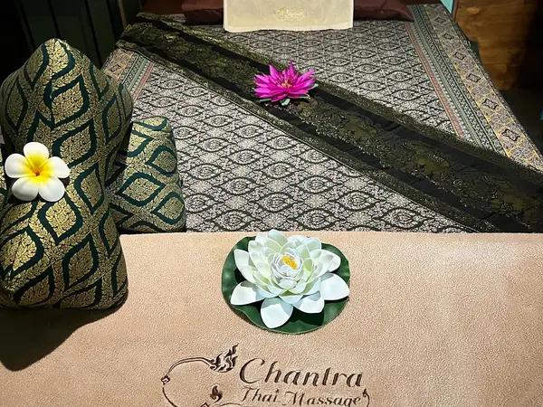 Thai massage room with patterned mats, decorative cushions, and artificial flowers