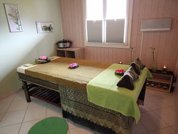 Cozy Thai massage room with two treatment tables, flowers, and candles