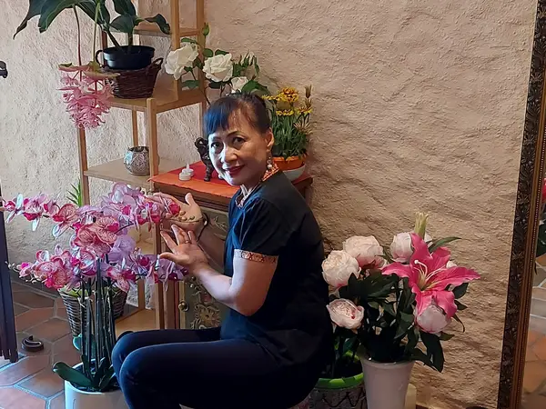 Decorated salon corner with flowers, shelves, and a seated woman