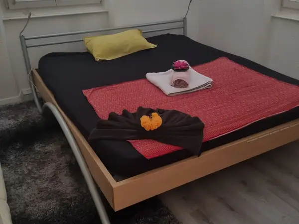 Massage room with a neatly made bed, folded towels, and floral decorations