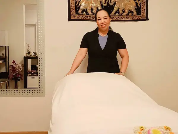Massage room with a practitioner beside a covered treatment table and wall decor