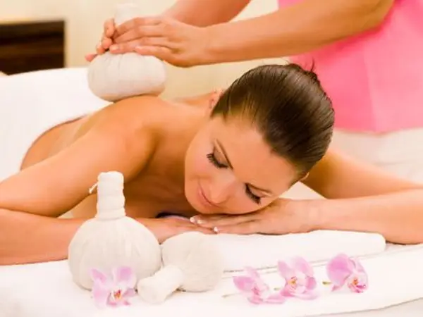 Massage room with woman receiving spa treatment on a white table