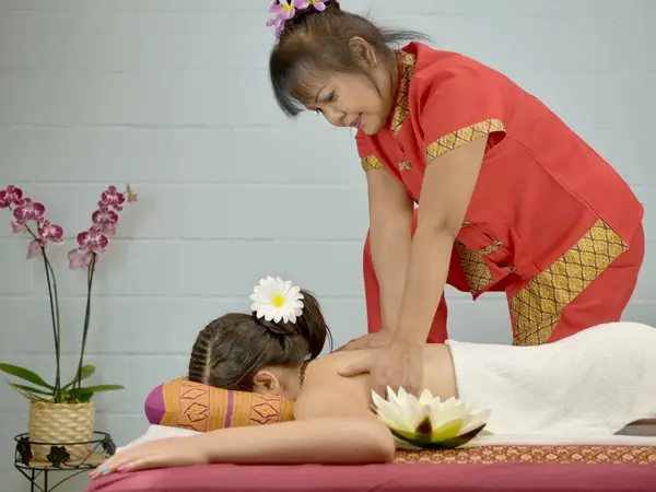 Thai massage therapist giving a back massage in a serene treatment room