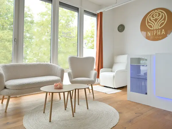 Bright salon waiting area with couch, chair, tables, and Nipha logo wall sign