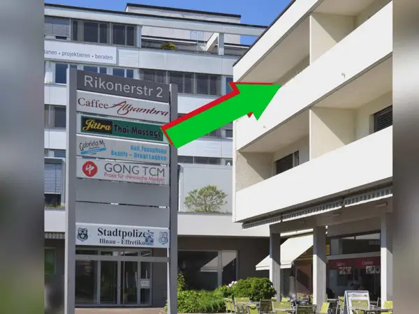 Exterior of a commercial building with a Jittra Thai-Massage signboard and arrow