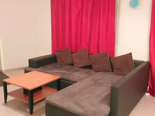 Massage room with sectional sofa, coffee table, and red curtains
