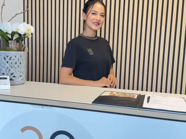 Reception desk with smiling staff, striped wall, and orchid arrangement