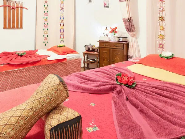 Bright Thai massage room with three covered massage beds and colorful wall decorations