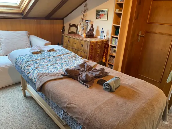 Warm massage room with a bed, folded towels, and wooden decor