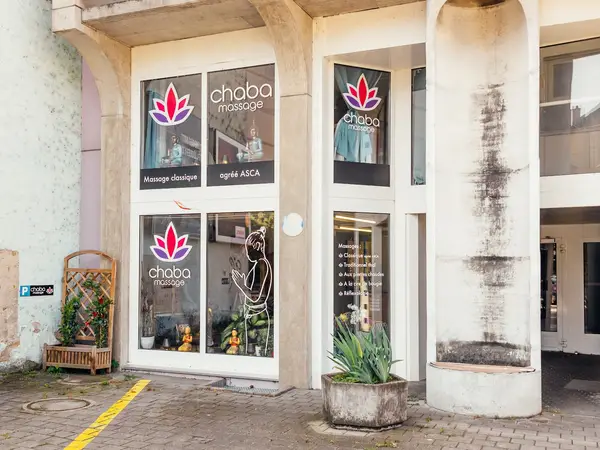 Exterior storefront of Chaba Massage with lotus logos and potted plants