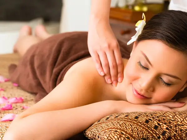 Woman receiving a shoulder massage on a patterned cushion indoors