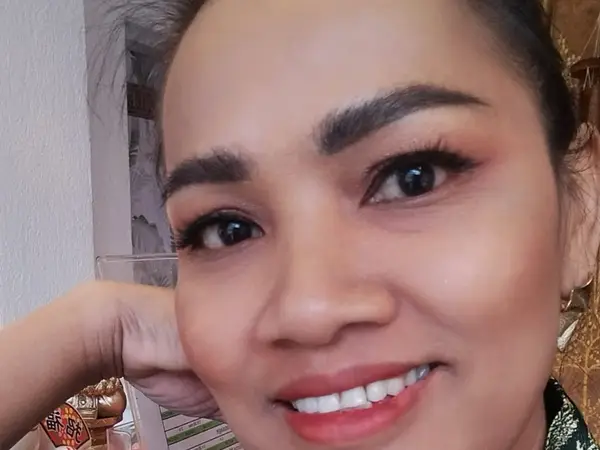 Close-up of a smiling woman indoors with a plain wall background
