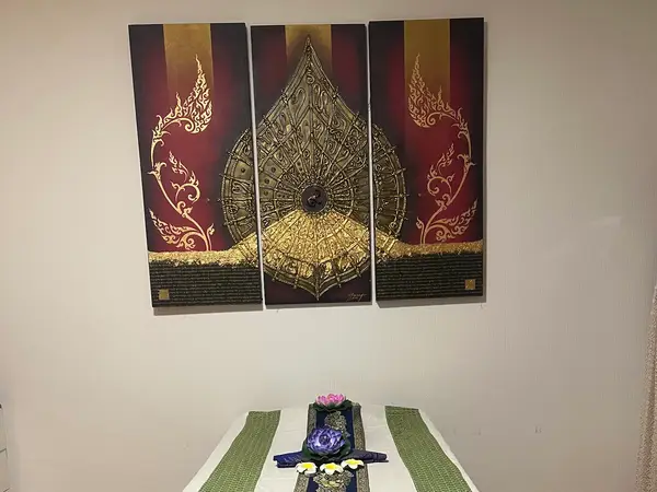 Massage room with a treatment bed and ornate Thai wall art
