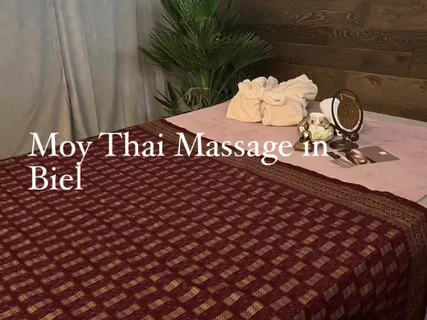 Massage table with patterned blanket, towels, mirror, and plant in a calm room