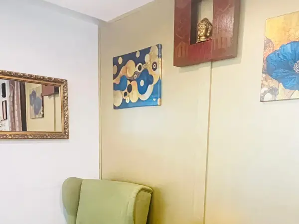 Small massage waiting area with green chair, mirror, and wall art