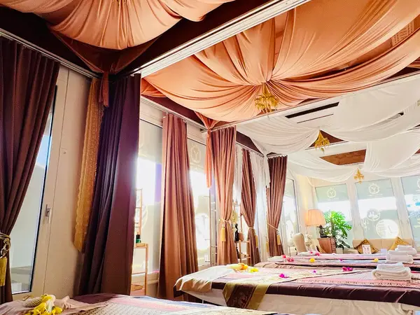 Elegant massage room with draped ceiling fabrics, curtained beds, and warm lighting