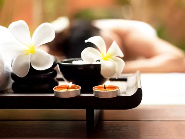 Spa tray with candles and flowers in a softly blurred massage room