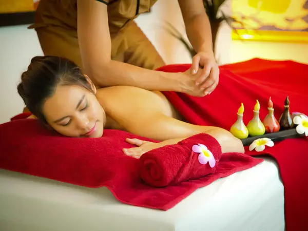 Massage room with a woman receiving a relaxing spa treatment on a red-covered table