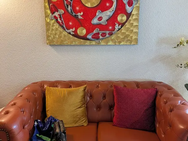 Cozy waiting area with a brown tufted sofa, colorful pillows, and wall art